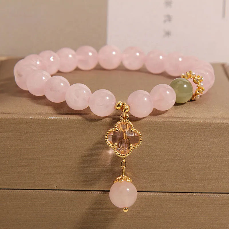 Pink crystal four-leaf clover pendant bracelet for women with rhinestones on alloy band.