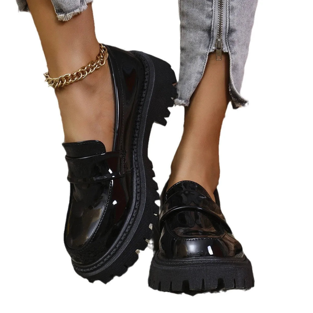 Black slip-on loafers with a chunky platform heel and thick rubber sole on a wooden floor.