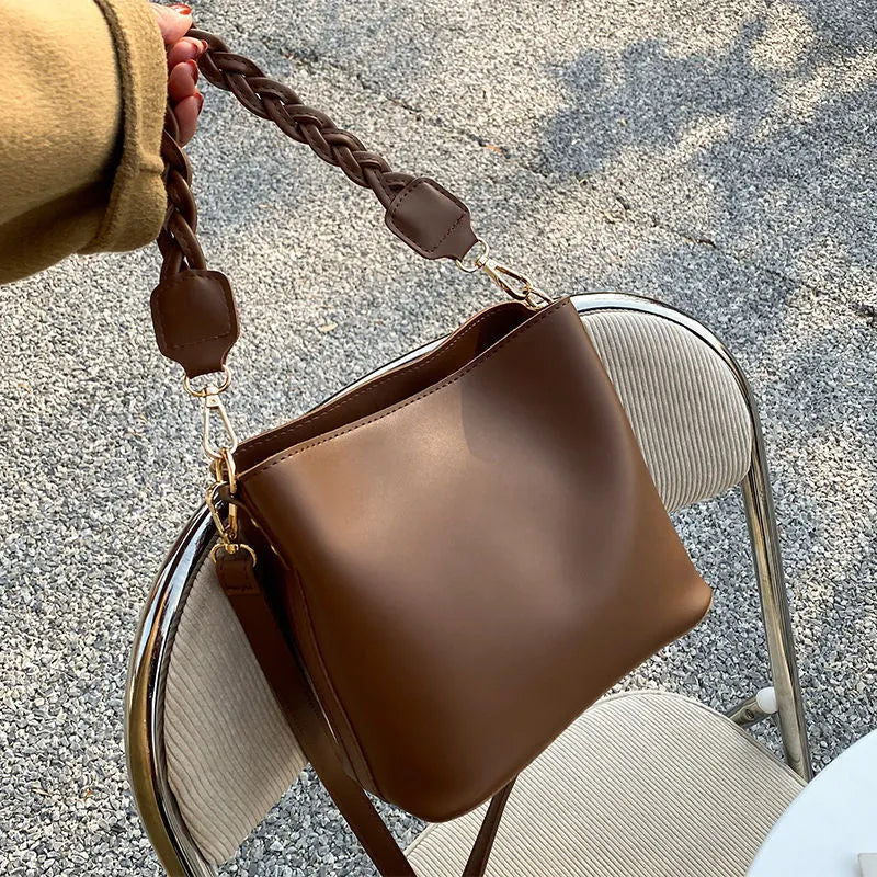 Khaki PU leather bucket bag with woven texture and a crossbody strap.