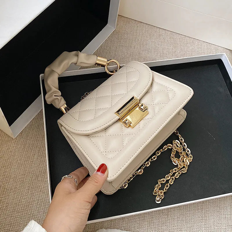 Purple rhombus-shaped women's shoulder bag with a chain strap on a white background.