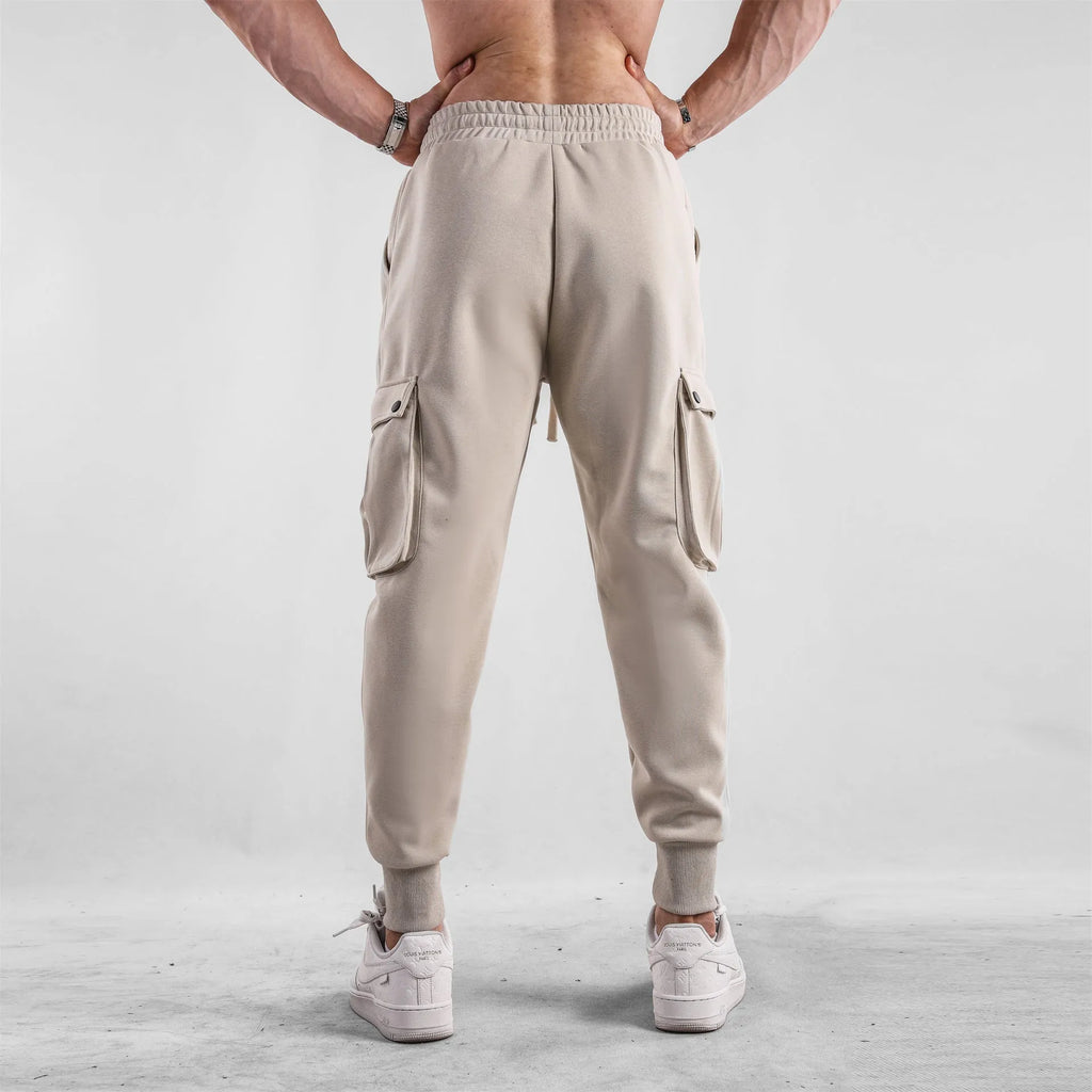 Men's loose grey cotton sports trousers with ankle ties and side pockets laid flat.