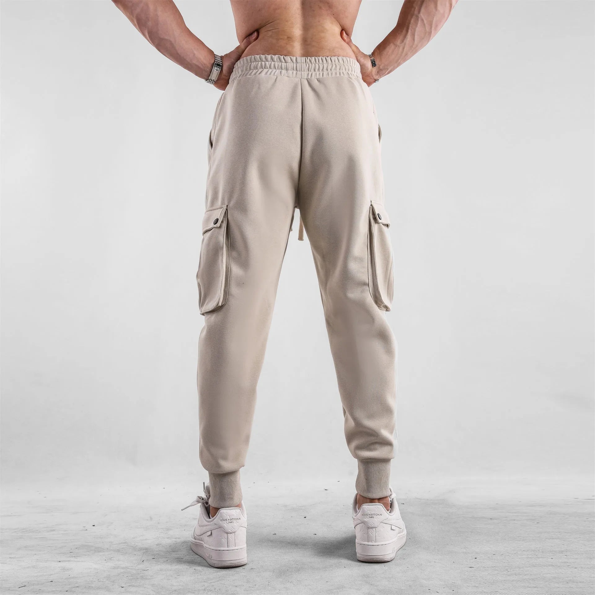 Men's loose grey cotton sports trousers with ankle ties and side pockets laid flat.