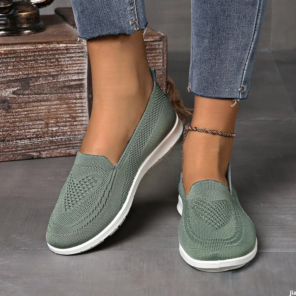 Women's beige canvas slip-on shoe with heart-shaped perforations and a flat sole.