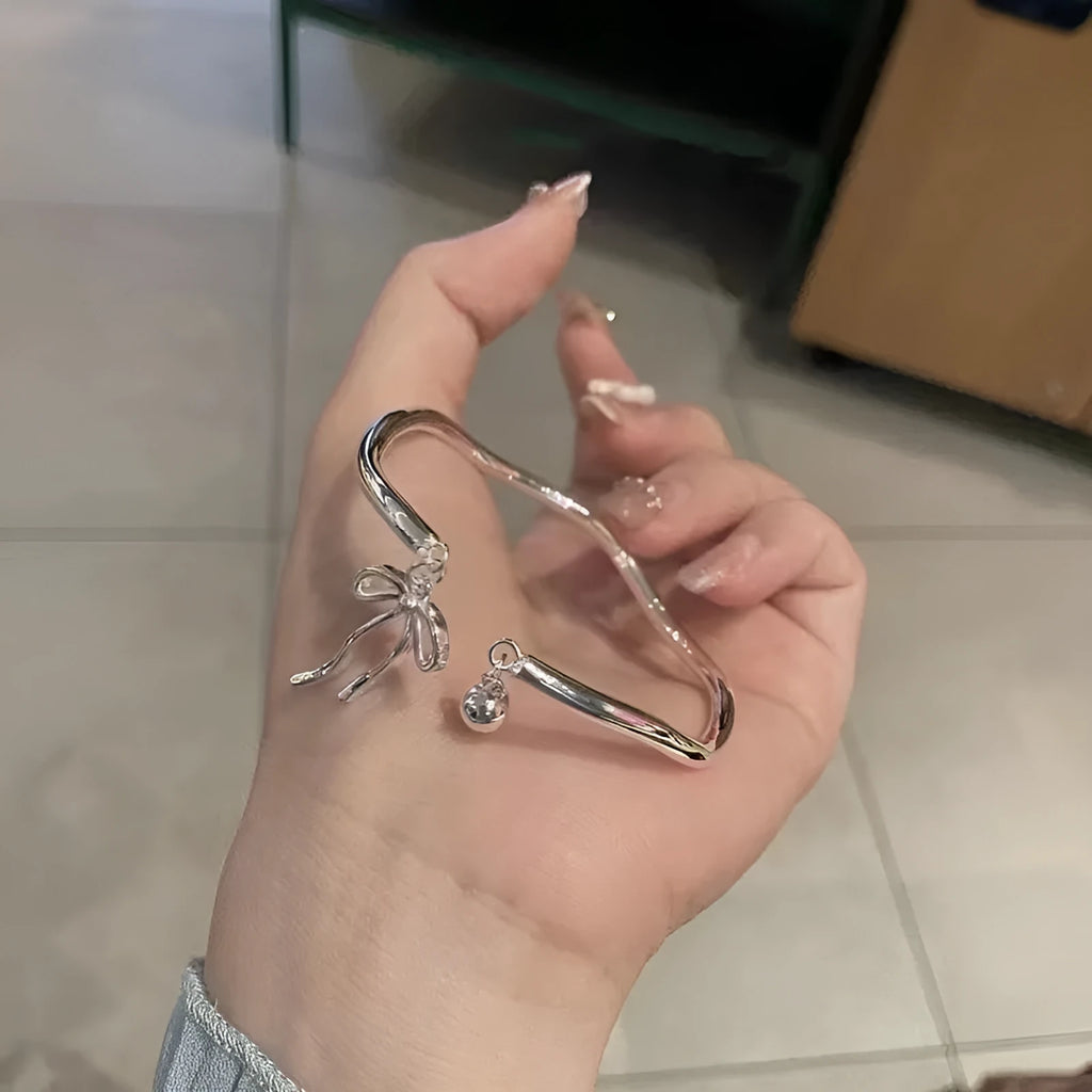 Silver adjustable bracelet with a bow charm and bell opening clasp