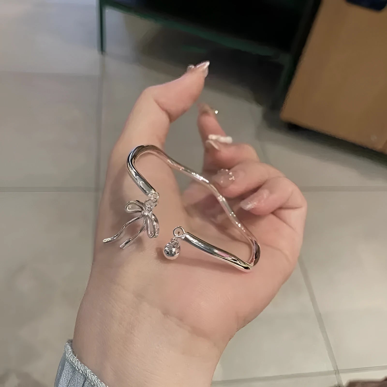 Silver adjustable bracelet with a bow charm and bell opening clasp