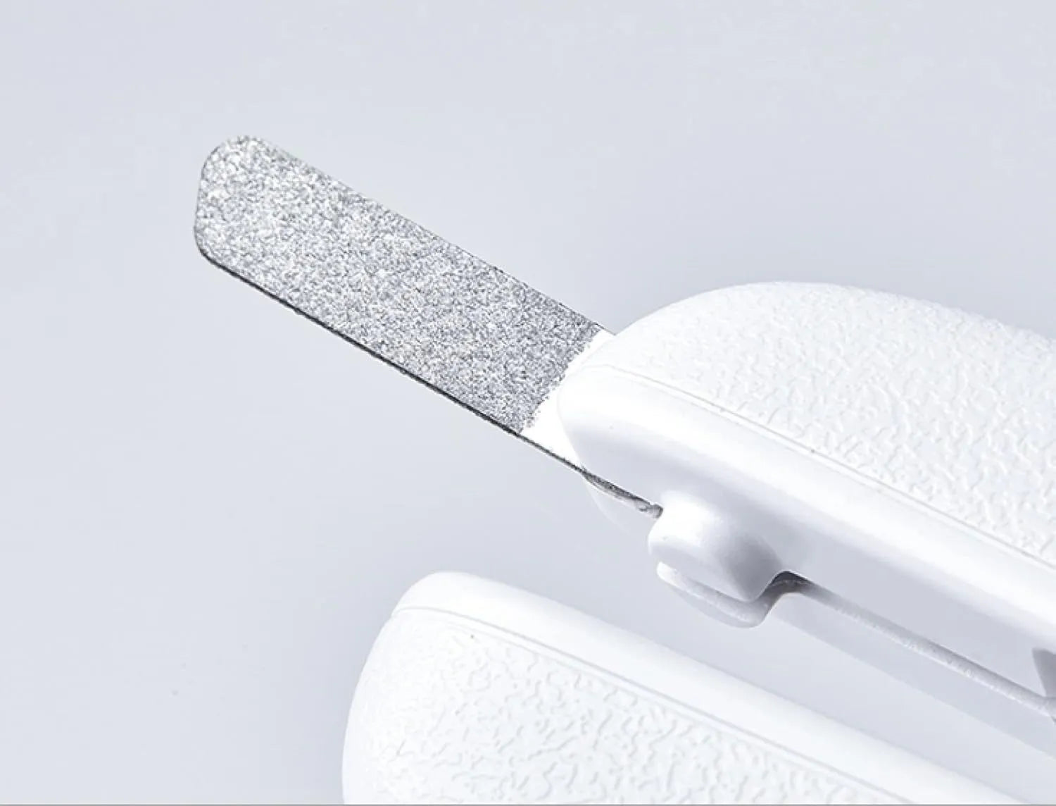 White pet nail clippers with LED light on blade and transparent anti-splash guard, shown with a nail file.