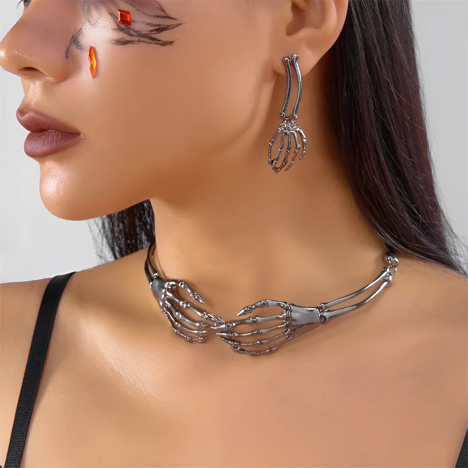 Silver alloy skull and ghost claw necklace with matching earrings set on a dark background.