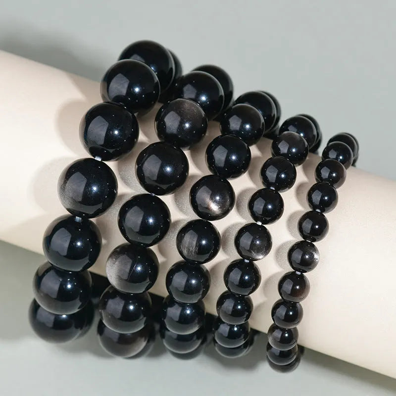 Hand-woven obsidian couple bracelets in various colours including black, silver, and rainbow eye obsidian