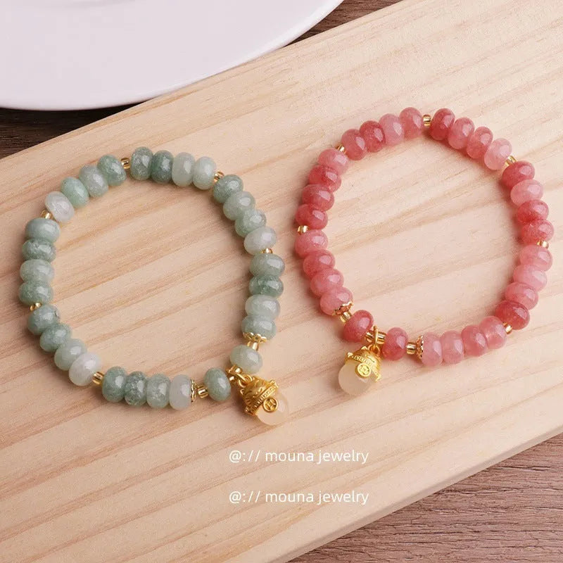 Women's lucky cat bracelet made from strung strawberry quartz or grey jade stones with zodiac charms.