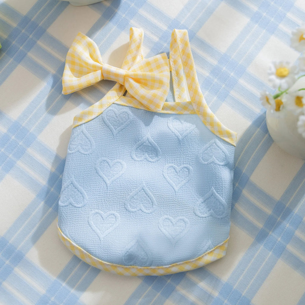 Small dog wearing a blue elastic vest with a heart texture bow on the front.