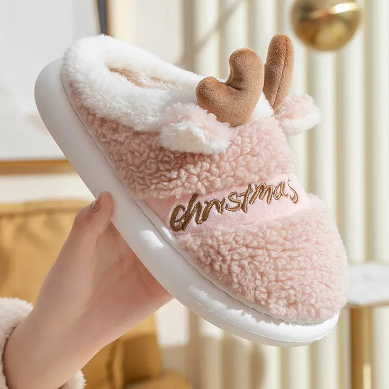 Pair of Christmas elk winter home slippers with suede upper and candy-coloured antler print on bedroom floor