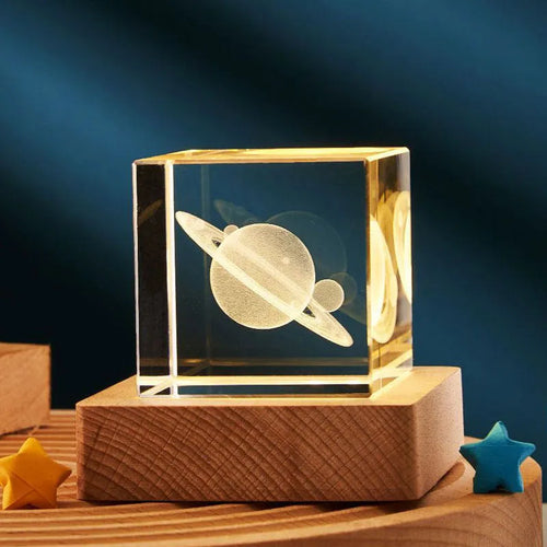 Transparent glass cube night lamp projecting a warm nebula light pattern on a desk.