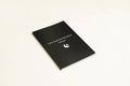 Black soft-touch dream journal notebook lying open on a table, showing ruled pages.
