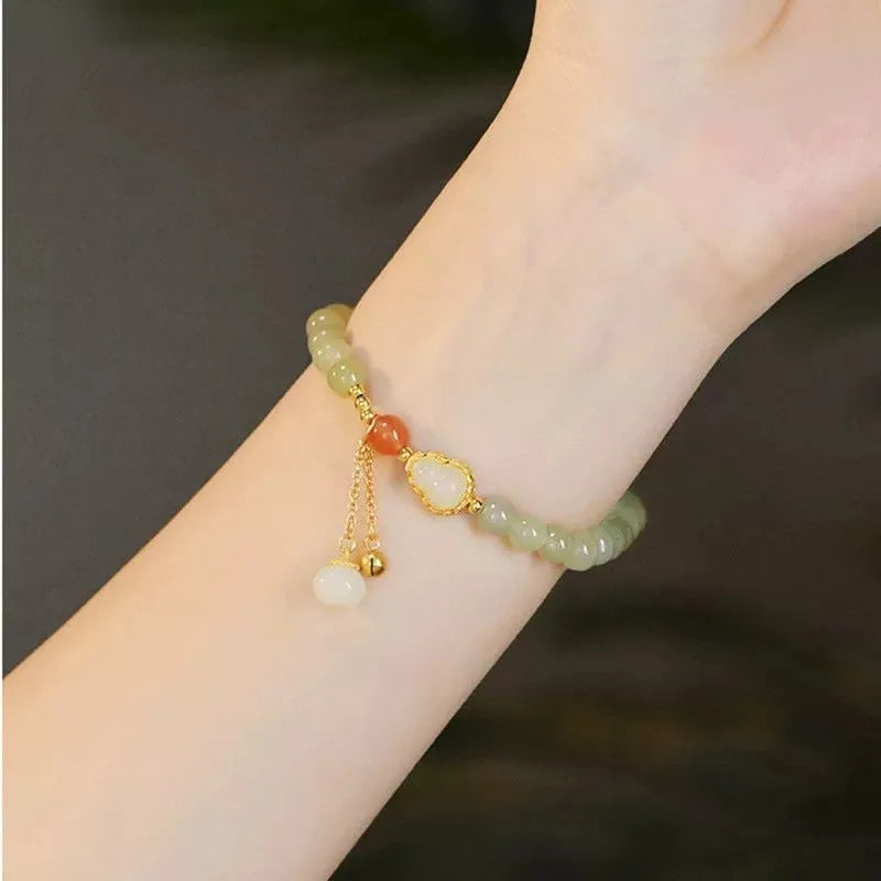 Hand-strung jade bracelet with a gold gourd charm and fu character charm.