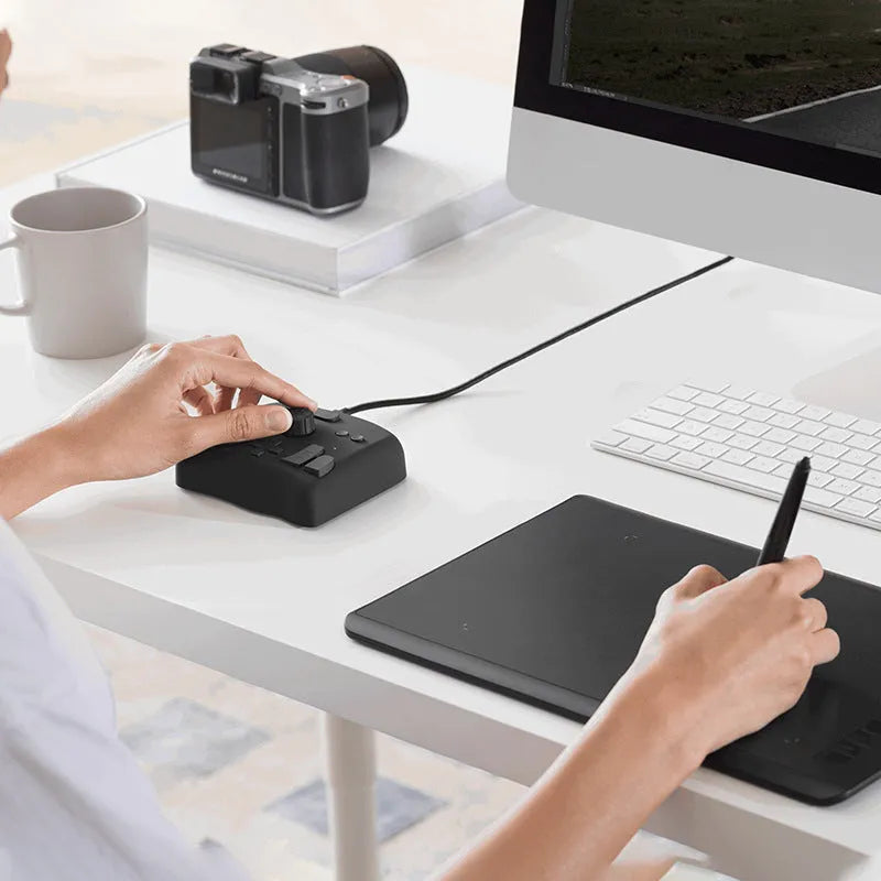TourBox NEO black USB video editing controller and auxiliary keyboard on a desk