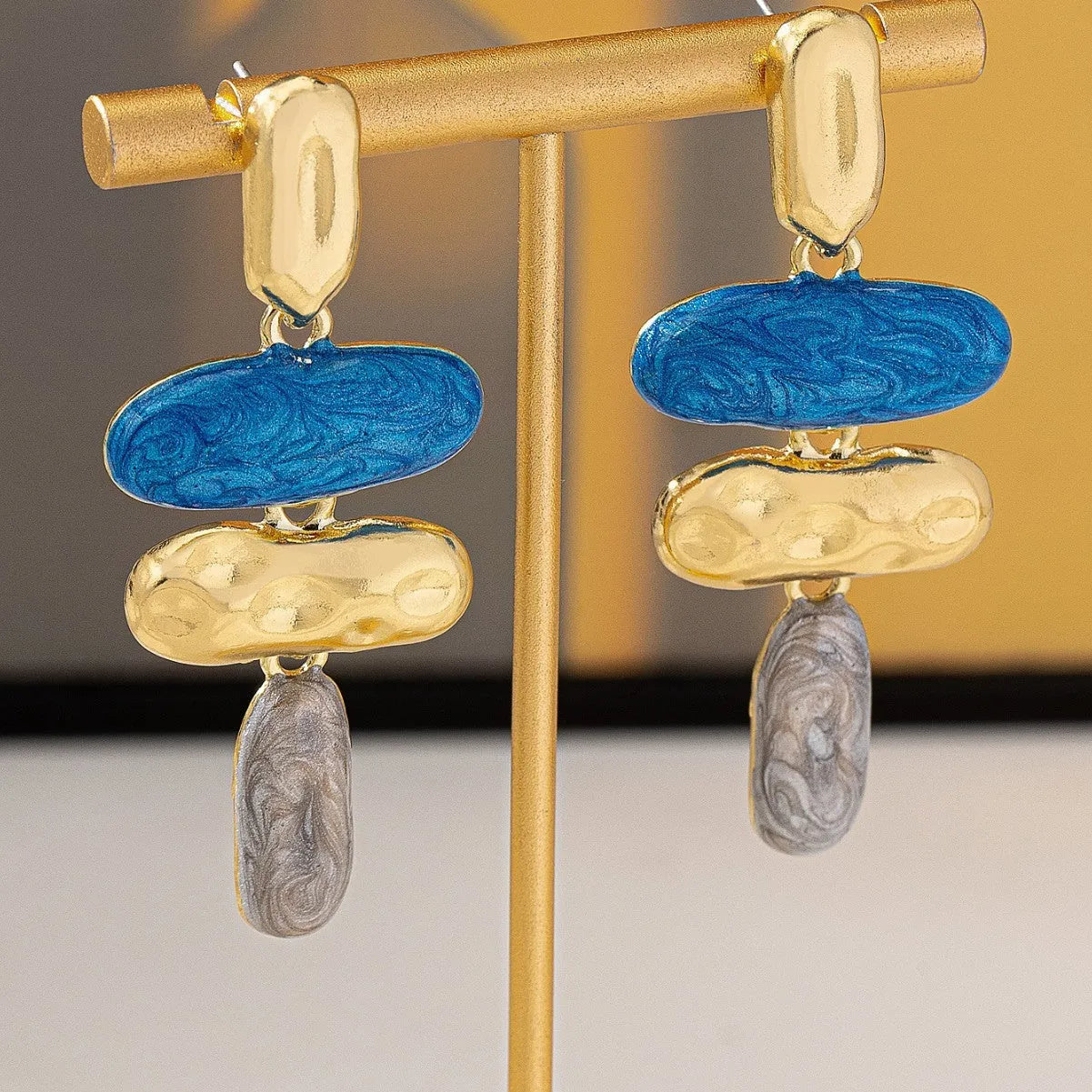 A pair of geometric-shaped stud earrings with a multicolour electroplated metal finish.