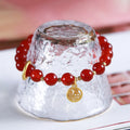 Close-up of a woven red agate bracelet showing bead detail and blessing card.