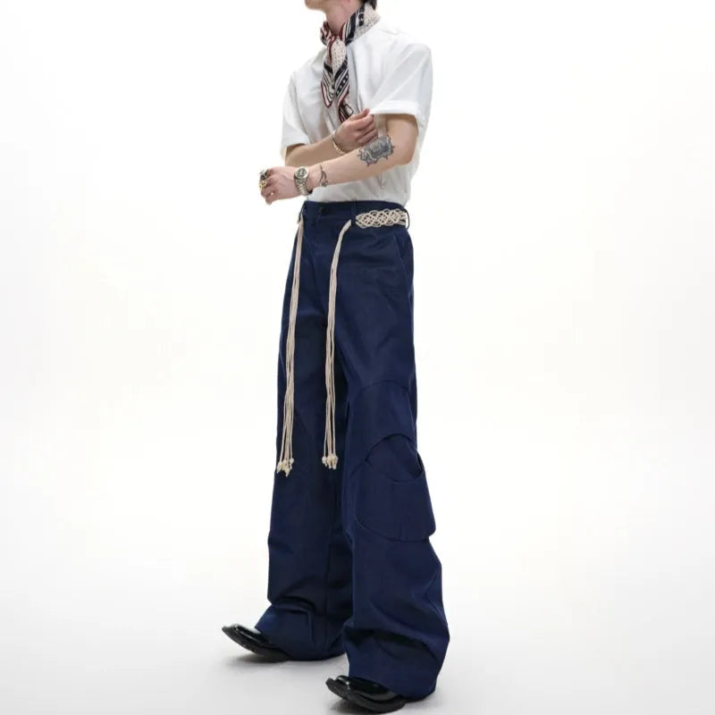 Men's dark coloured straight-leg jeans with heavy 3D cutting, belt-loop stitching, and decorative zipper details