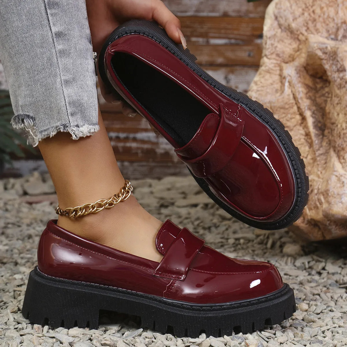 Black slip-on loafers with a chunky platform heel and thick rubber sole on a wooden floor.