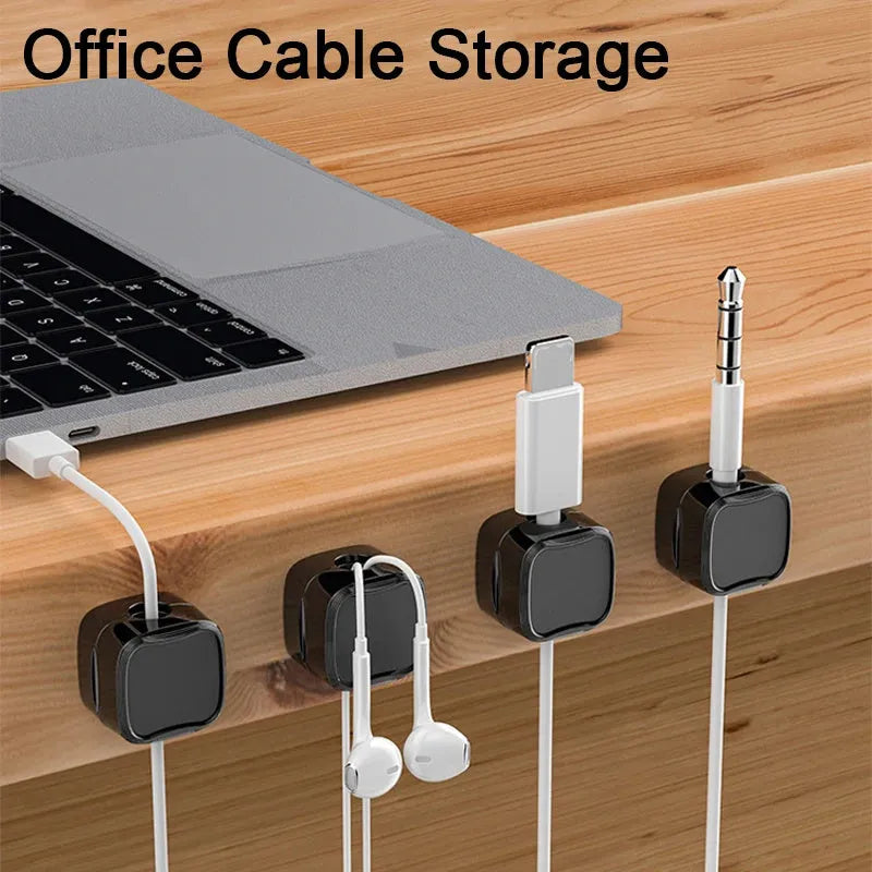 White and black magnetic adhesive cable clips holding a USB cable against a wooden desk.