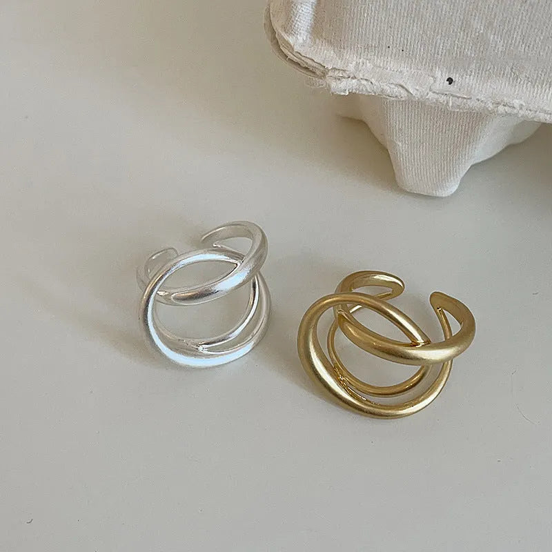 Geometric open ring with three-dimensional interlaced matte metal construction in gold or silver finish