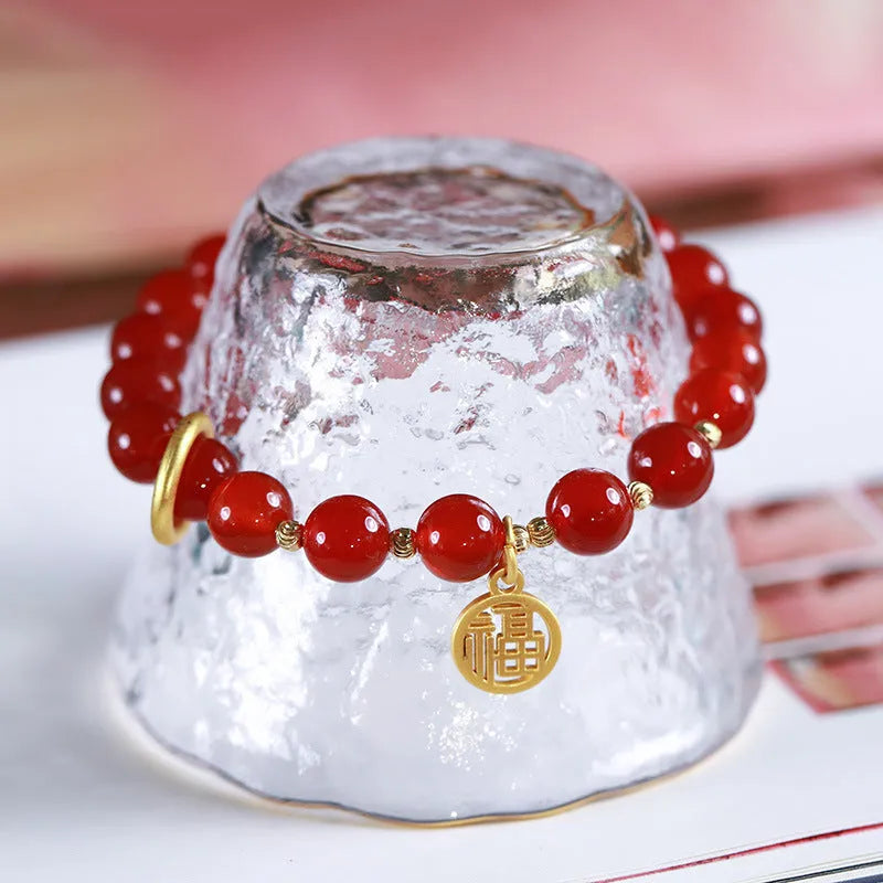 Close-up of a woven red agate bracelet showing bead detail and blessing card.