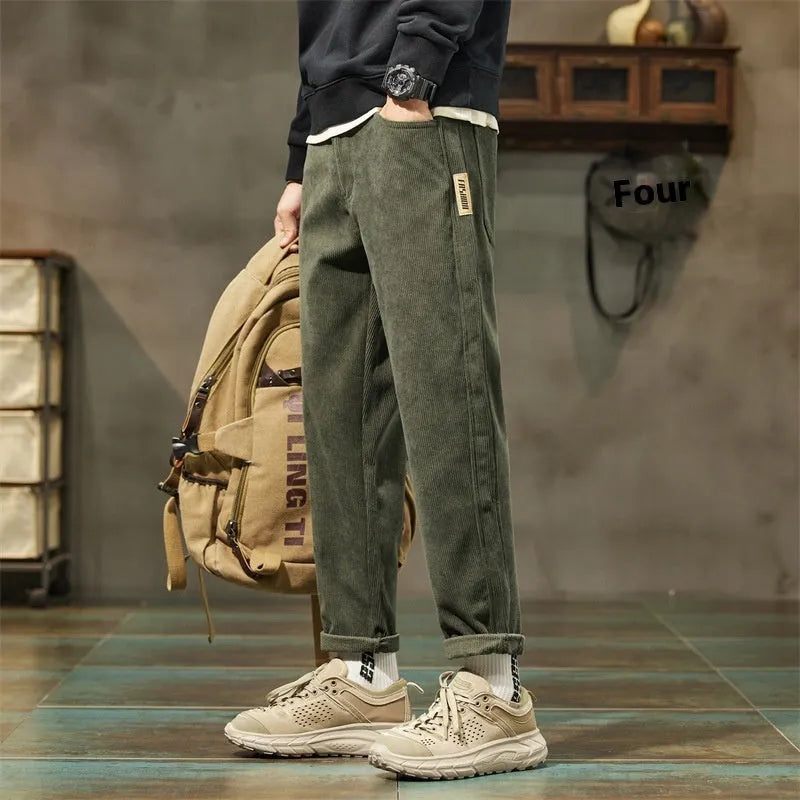 Man wearing tapered straight-leg corduroy trousers in army green, showing mid-rise waist and street style.