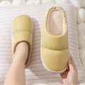 A pair of thick-soled house slippers with an artificial leather upper and plush lining, shown in a choice of colours.