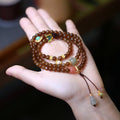 Brown Hetian jade bracelet with three-ring design featuring carved gourd and butterfly charms, silver-plated connectors