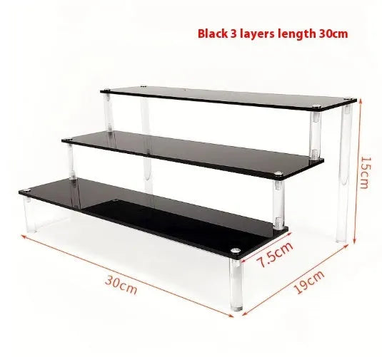Transparent acrylic ladder display rack with three trapezoidal tiers showing blind box figurines on a desk
