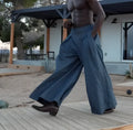 Grey men's trousers with pleated waist and wide-leg fit laid flat.