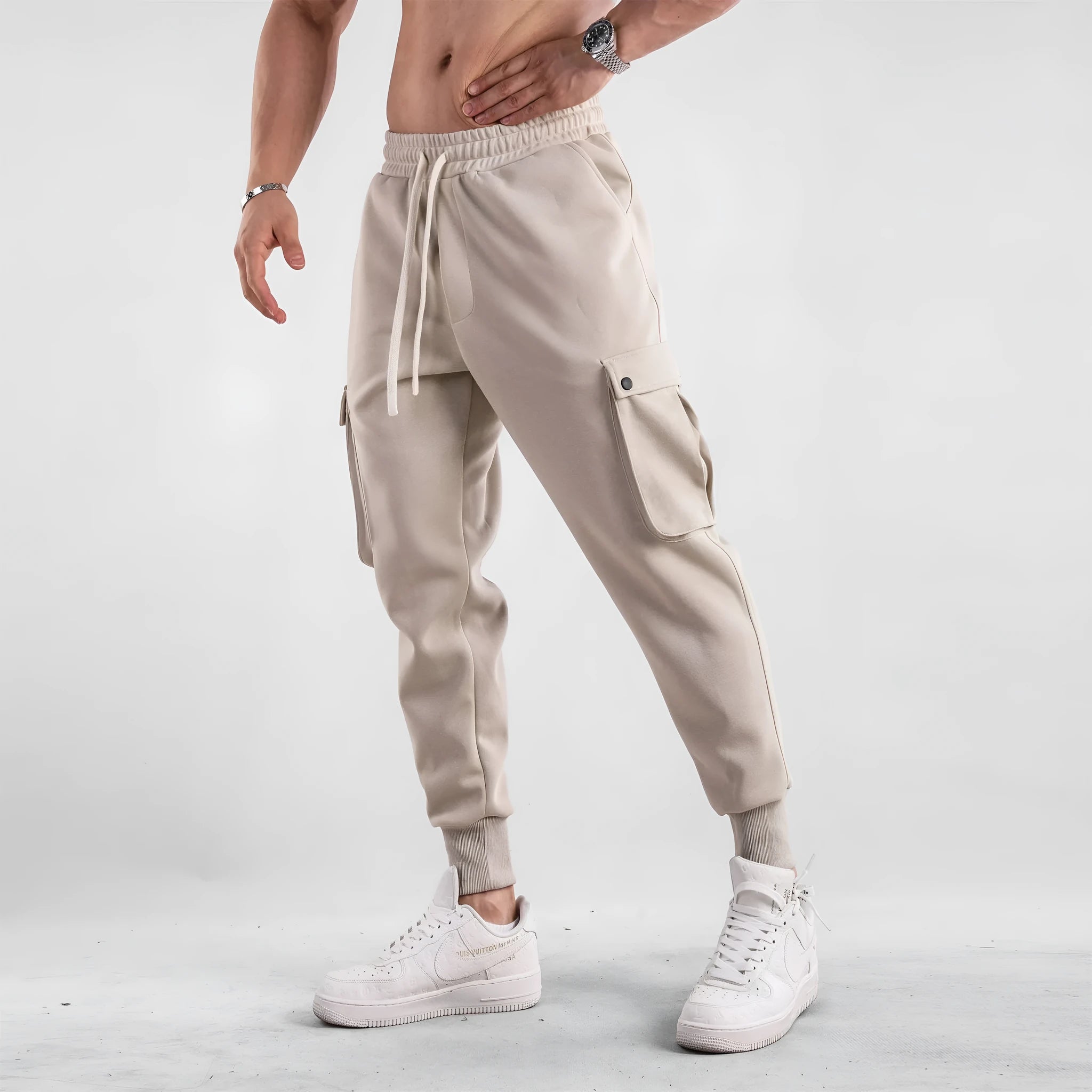 Men's loose grey cotton sports trousers with ankle ties and side pockets laid flat.