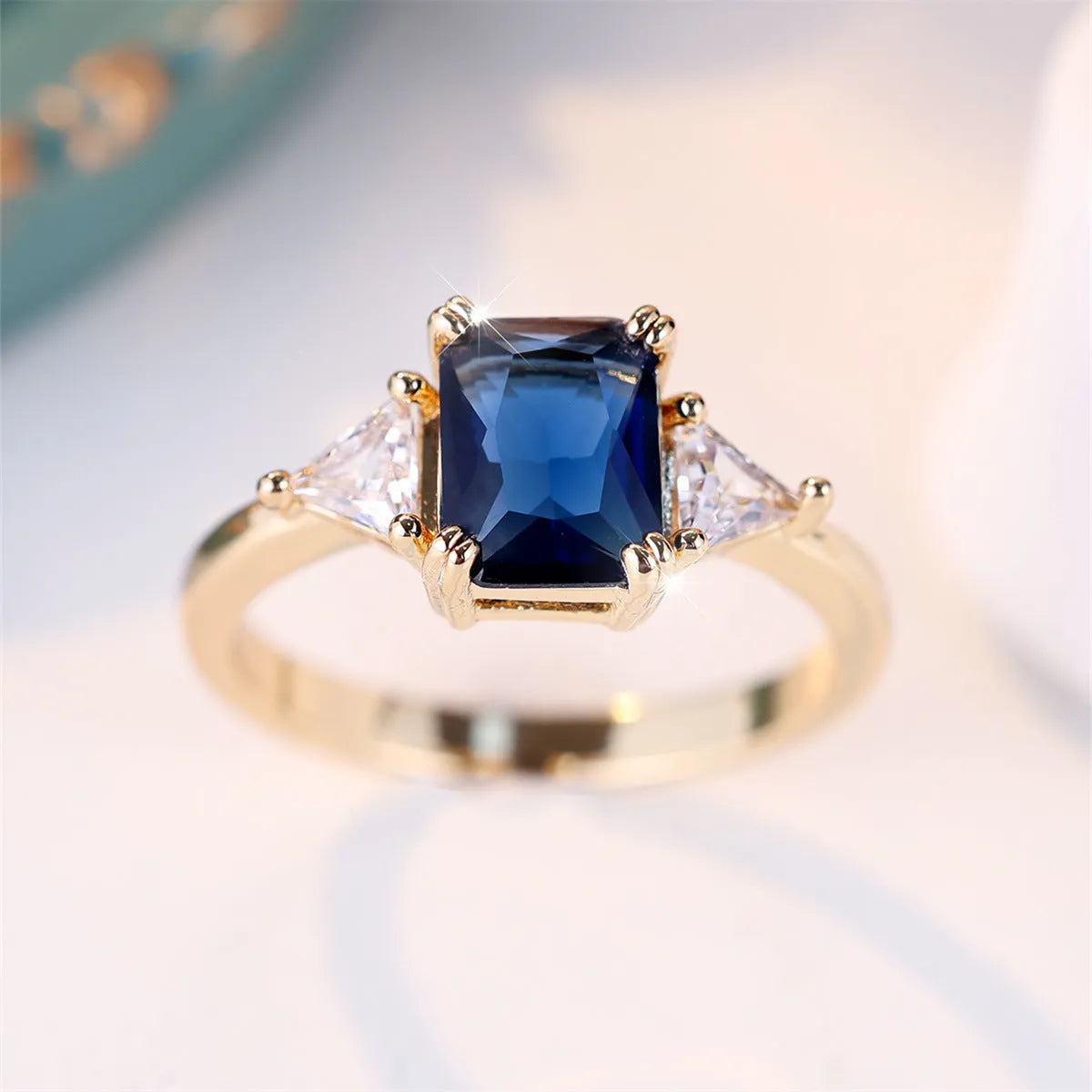 A rectangular copper fashion ring for women with a gold sapphire blue finish.