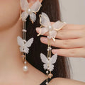 White butterfly-shaped drop earrings with sparkling rhinestone pearls and long white lace tassels.
