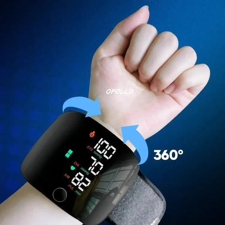 Black wrist blood pressure monitor with USB charging cable on a table.