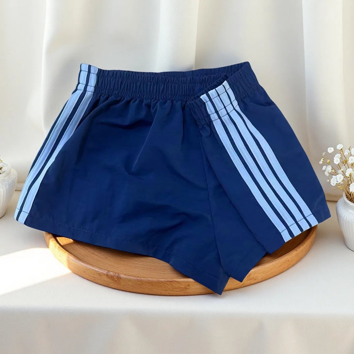 Men's navy blue high-waist nylon sports shorts laid flat, showing casual style and micro-elastic fabric.