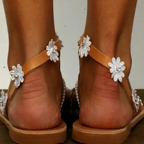 Brown women's Roman sandals with floral embroidery, flat rubber sole, and sleeve-on design.