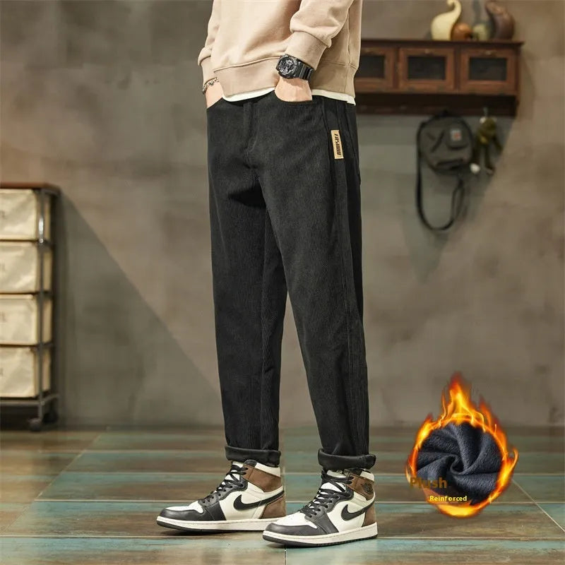 Man wearing tapered straight-leg corduroy trousers in army green, showing mid-rise waist and street style.