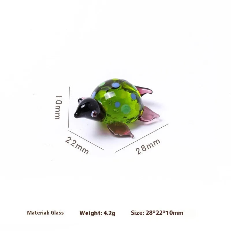 Handmade geometric glass turtle desktop ornament in a multicolour design on a wooden surface.