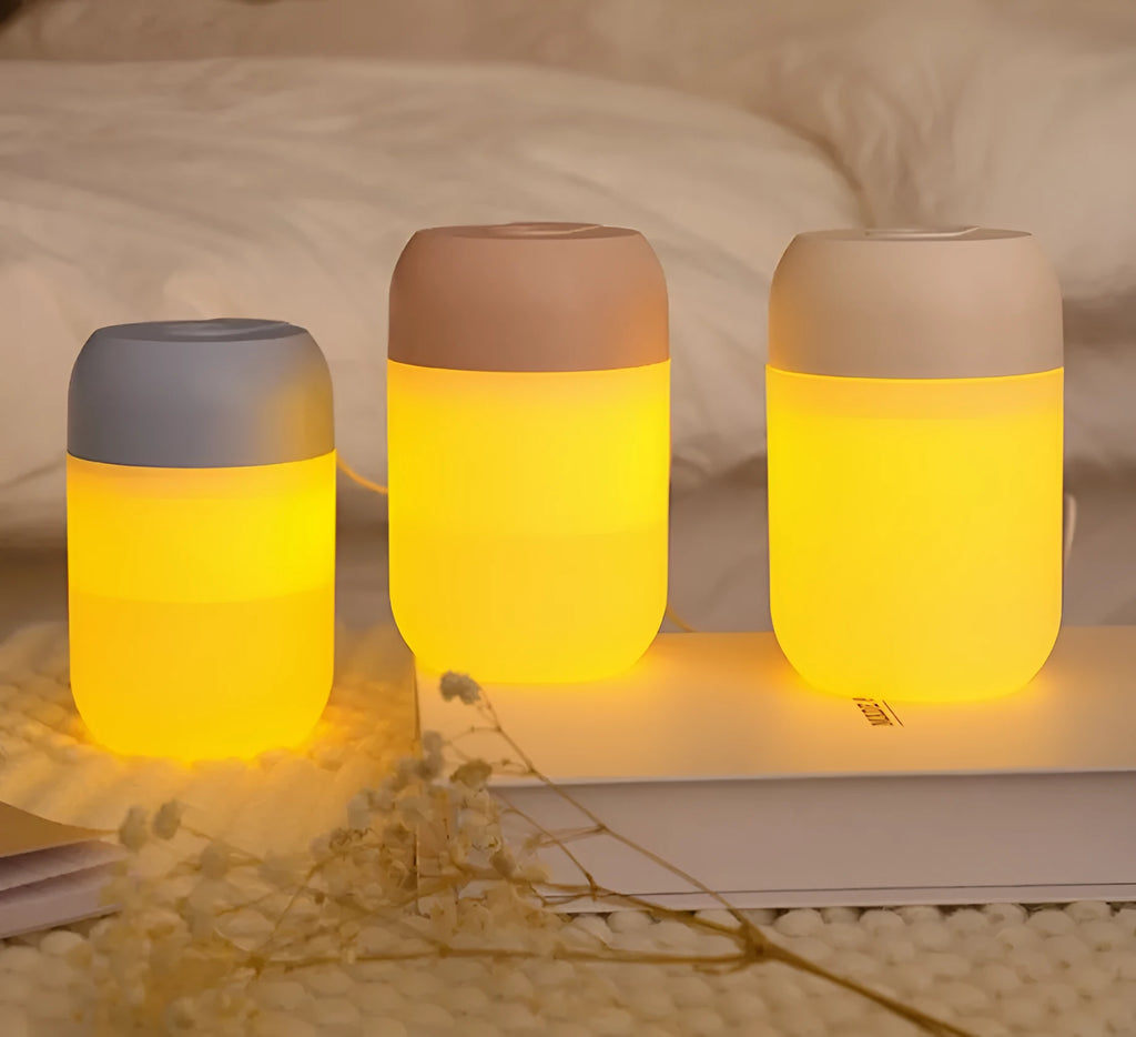 Small white cylindrical USB-powered humidifier with charging cable on a desk.