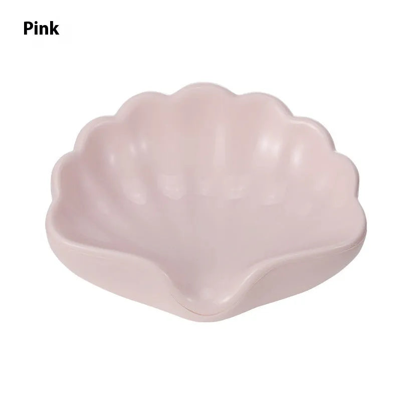 White or pink plastic shell-shaped soap dish for bathroom countertop or shower storage.