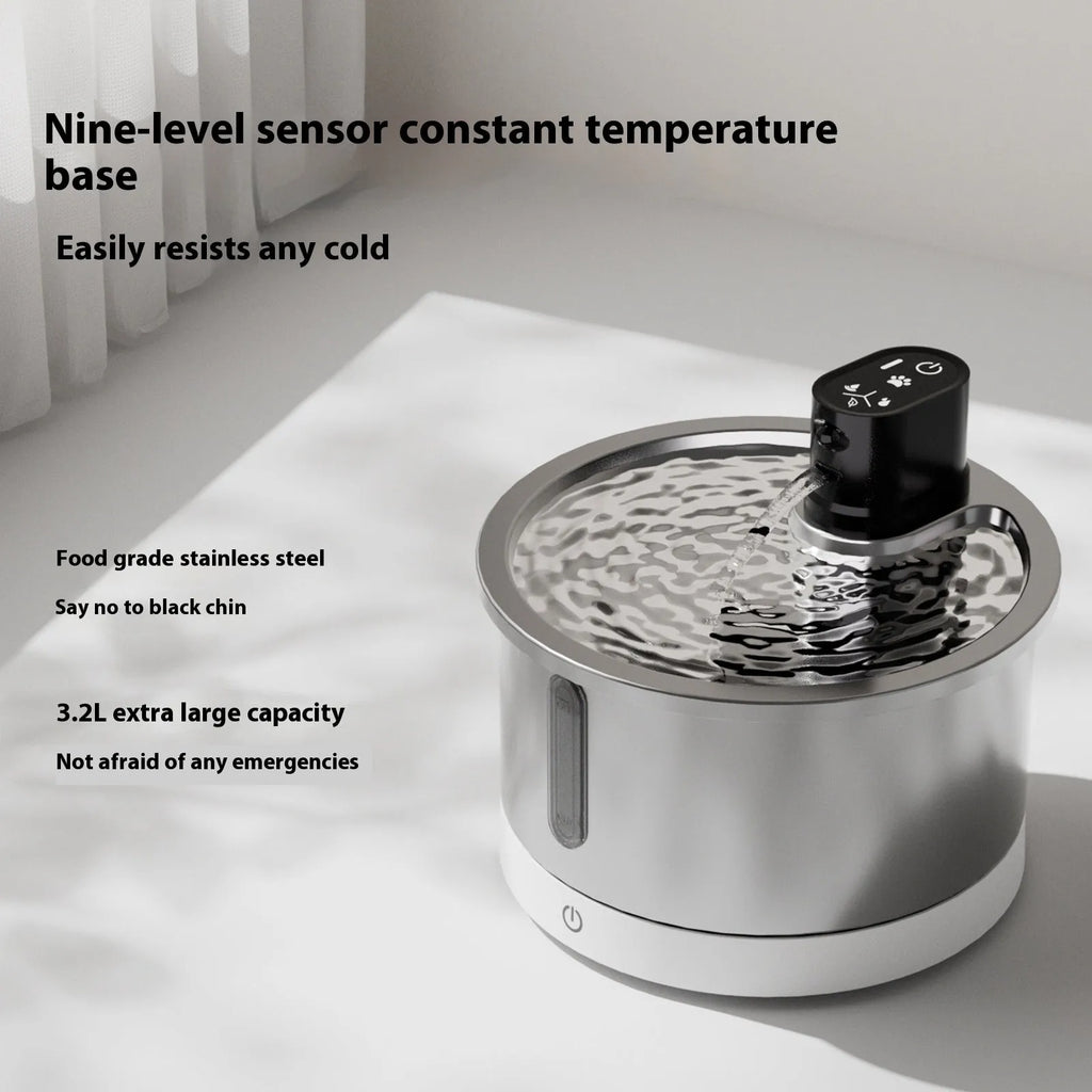 White stainless steel heated pet water fountain with a constant temperature base on a wooden floor.