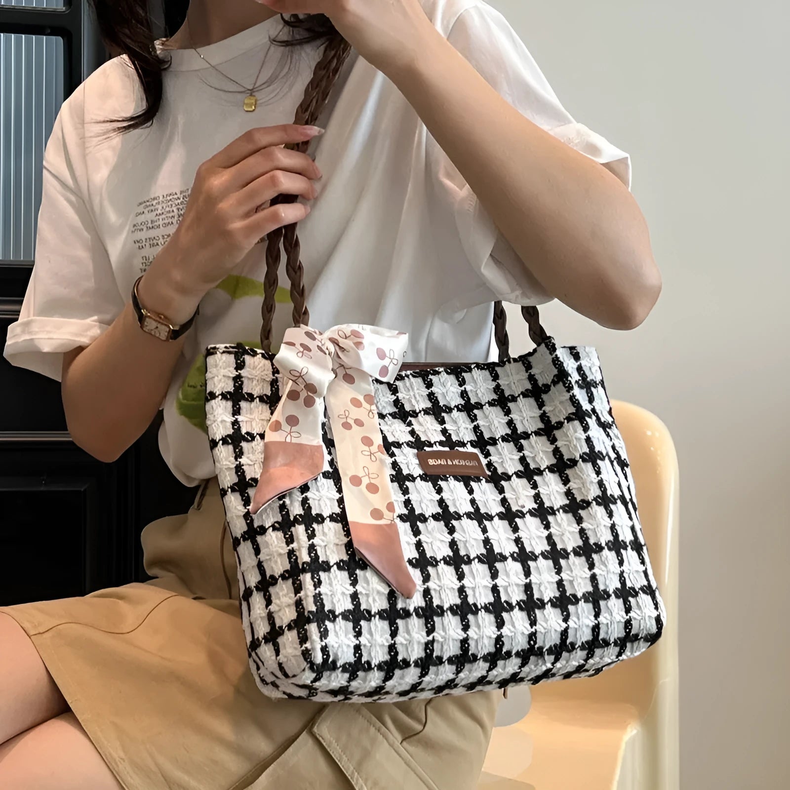 A black woven wool horizontal square shoulder bag showing external sandwich pocket and internal organiser compartments.