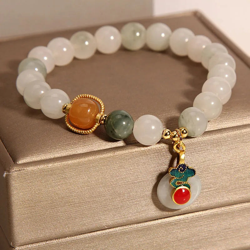 Close-up of a women's ice jade bracelet with a xiangyun peace buckle and pearl detail.