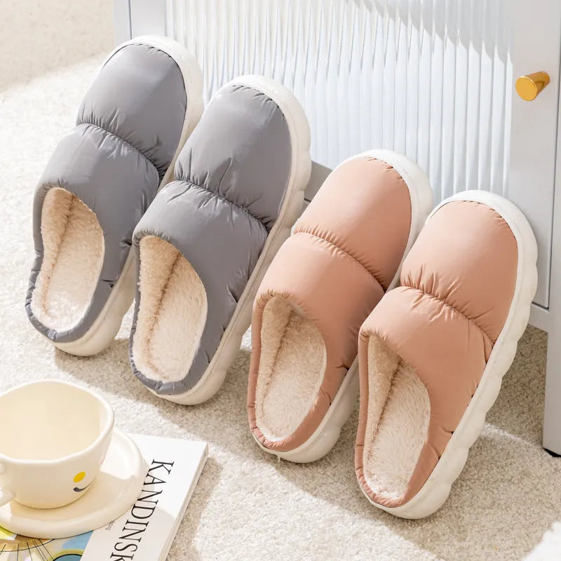 A pair of thick-soled house slippers with an artificial leather upper and plush lining, shown in a choice of colours.