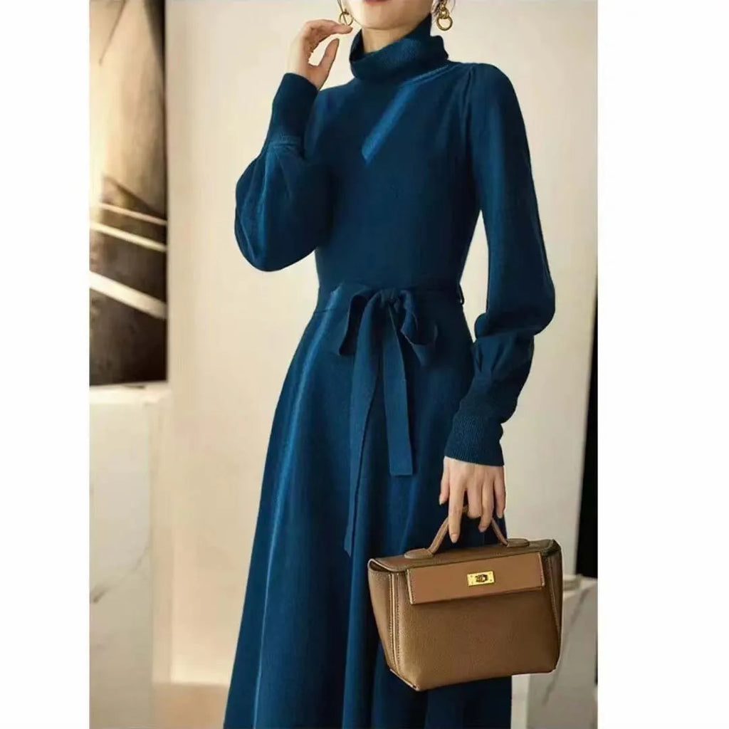 Adult woman wearing a rose red loose-knit turtleneck sweater dress with a flared midi skirt and elastic waist.