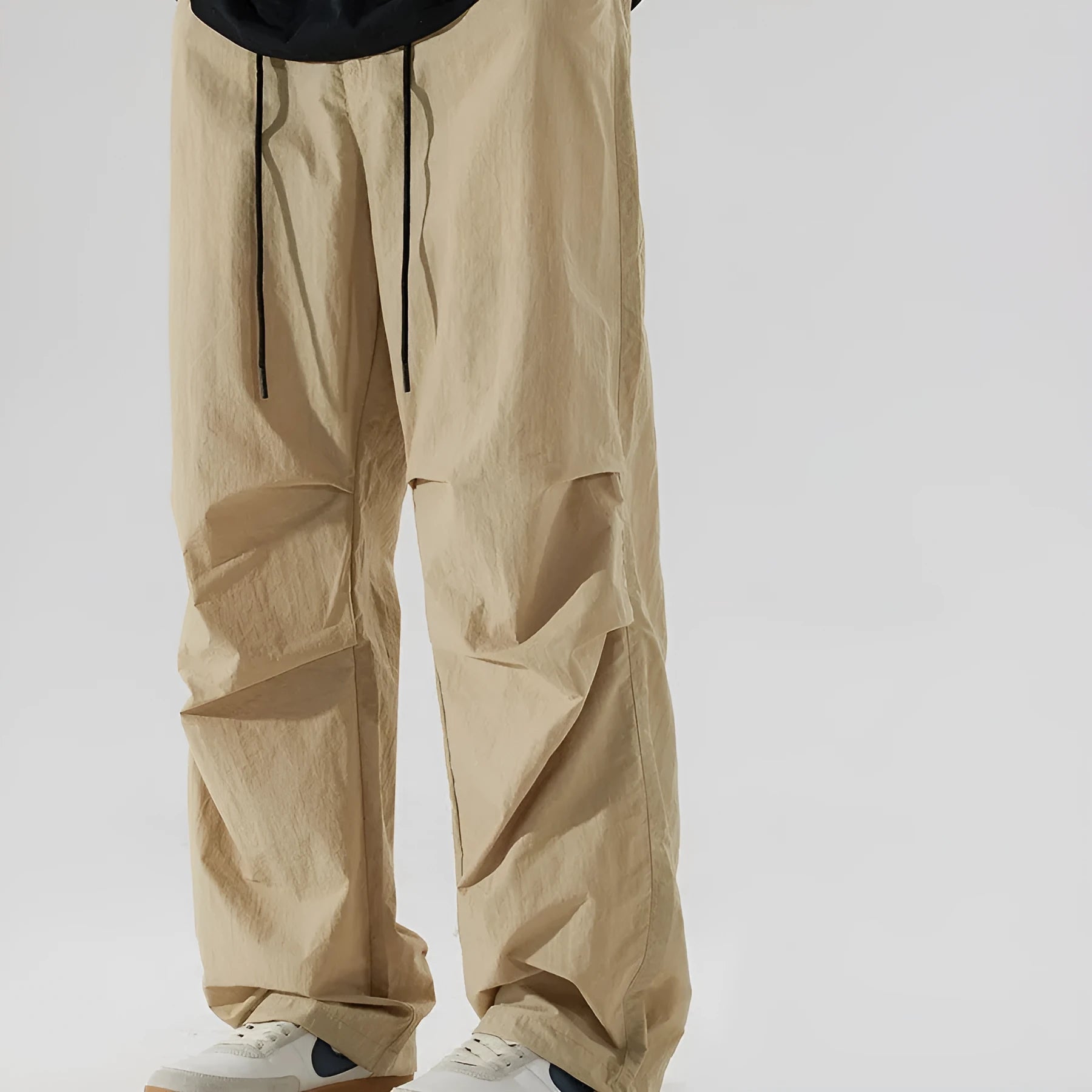 Man wearing thin ice silk loose straight leg casual trousers in a neutral colour with an elasticated waistband.