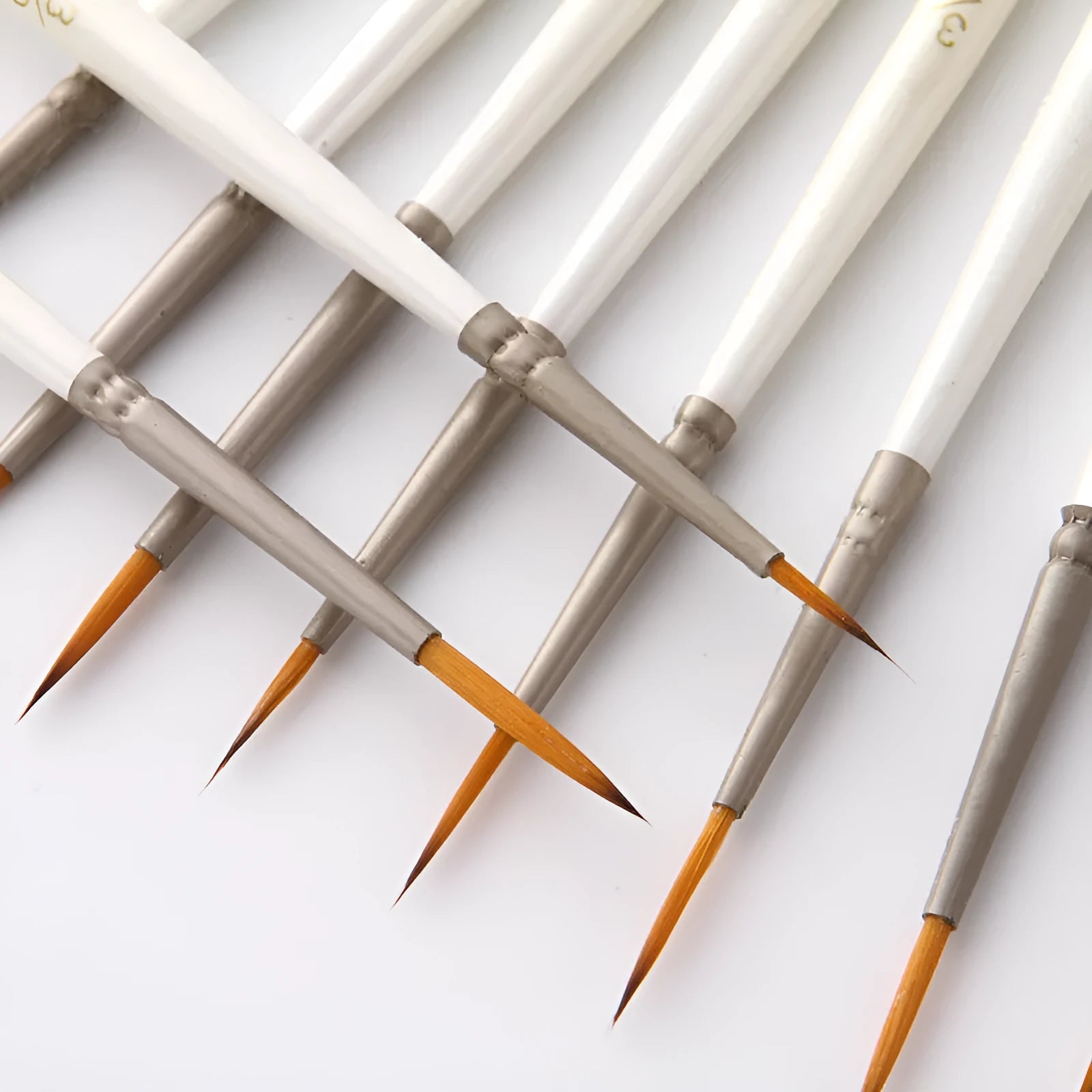 Set of 12 pearl white artist painting brushes with wooden handles and nylon wool fibres.