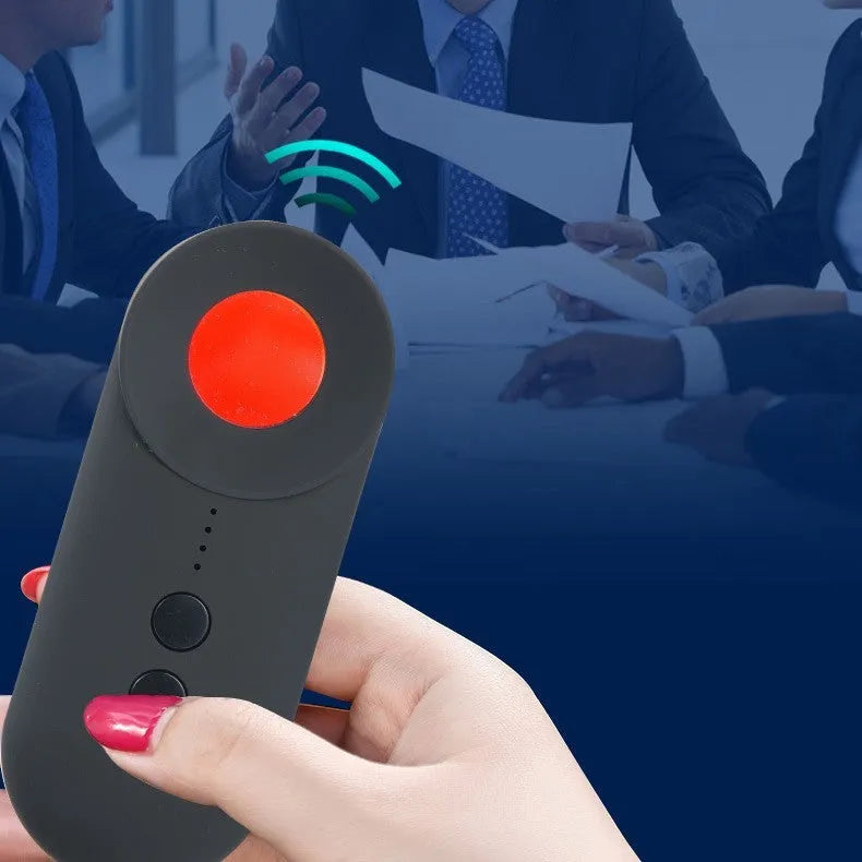 Black portable GPS and hidden camera detector with USB charging cable on a grey background.