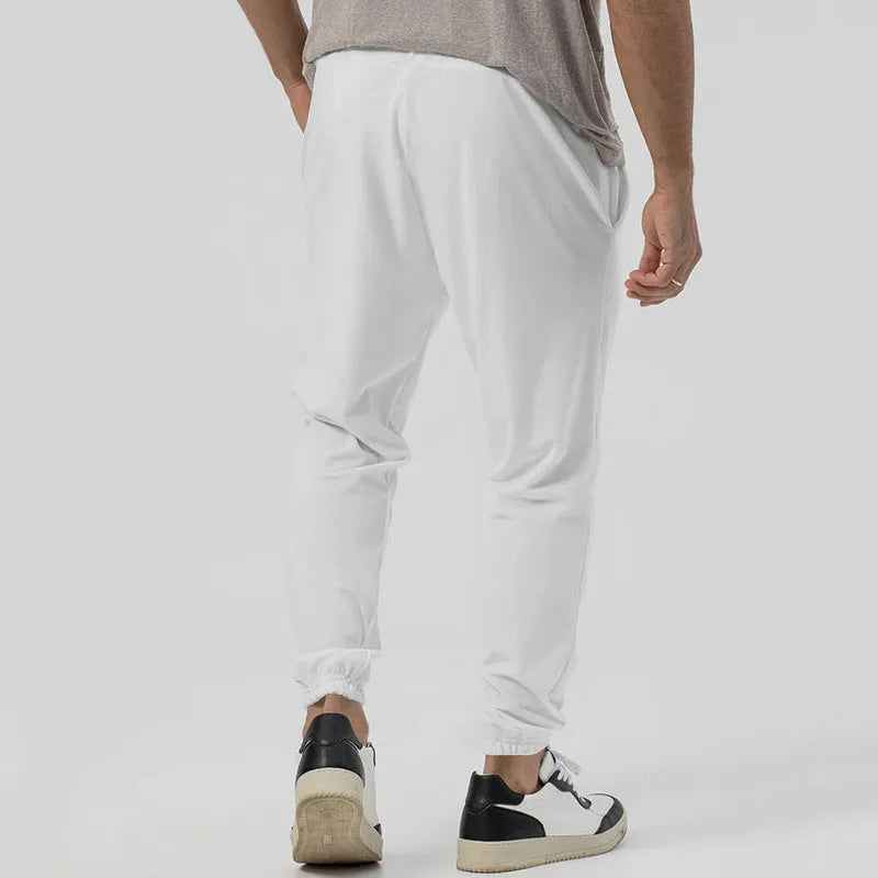 Man wearing grey loose tapered cotton blend track sweatpants, showing straight-leg style.